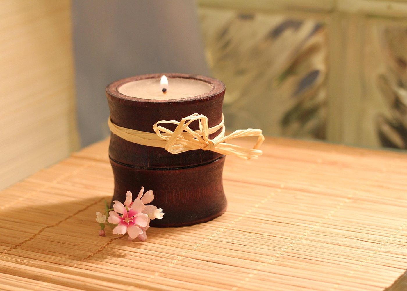 Bougie allumée et fleur sur une natte de bambou