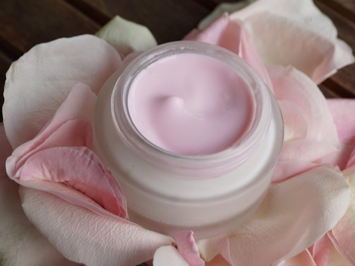 Pot de crème de soin entouré de roses
